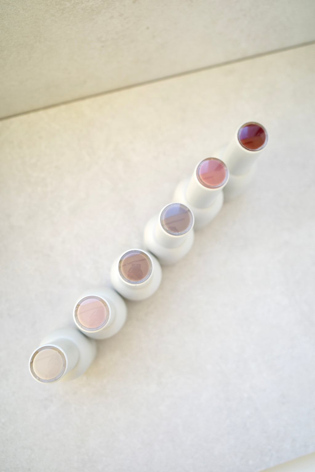 Set of ANGELIQ gel polish bottle with colorful lids on a light surface