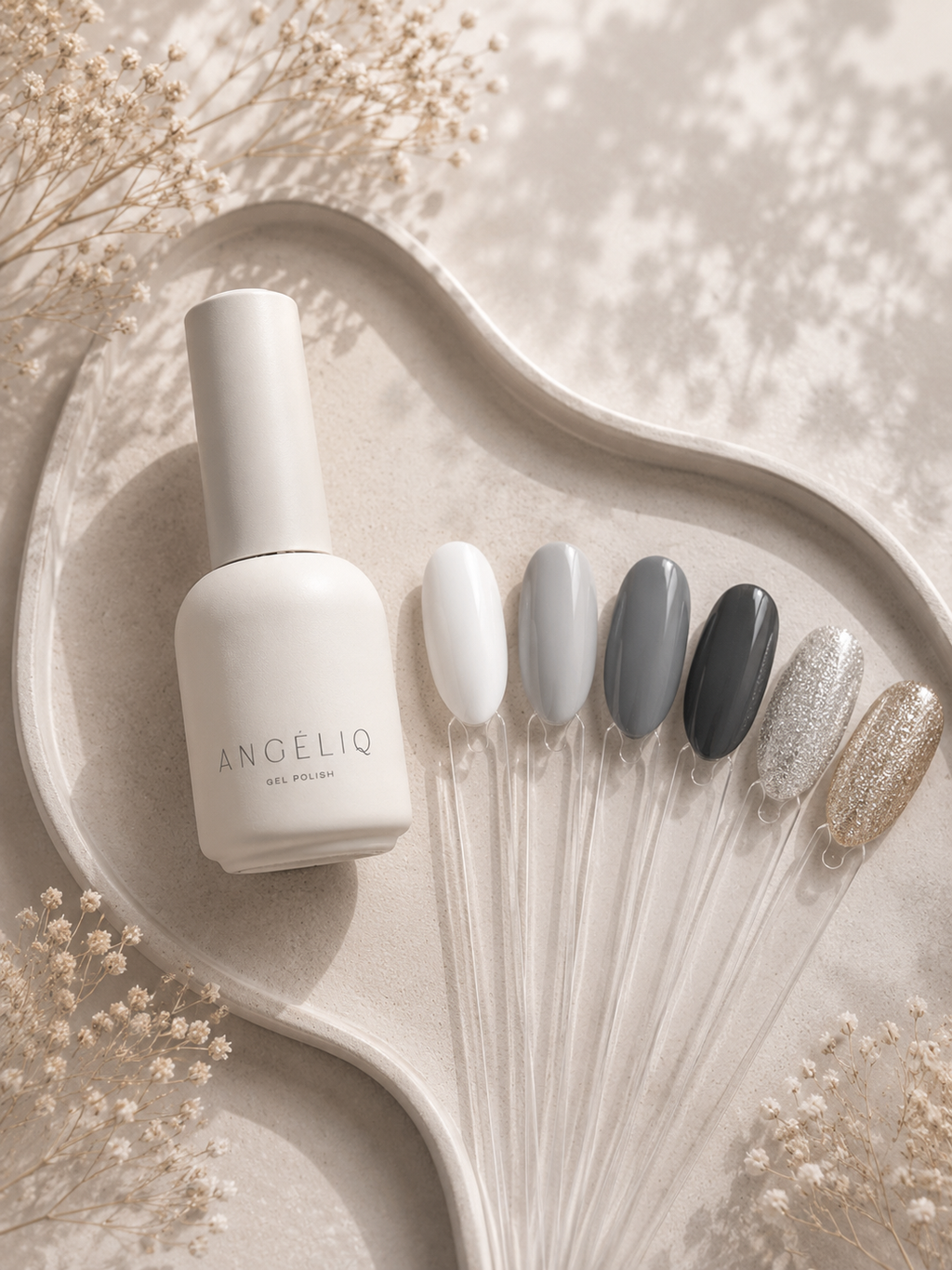 ANGELIQ nail polish bottle with nail samples on a decorative tray with dried flowers.