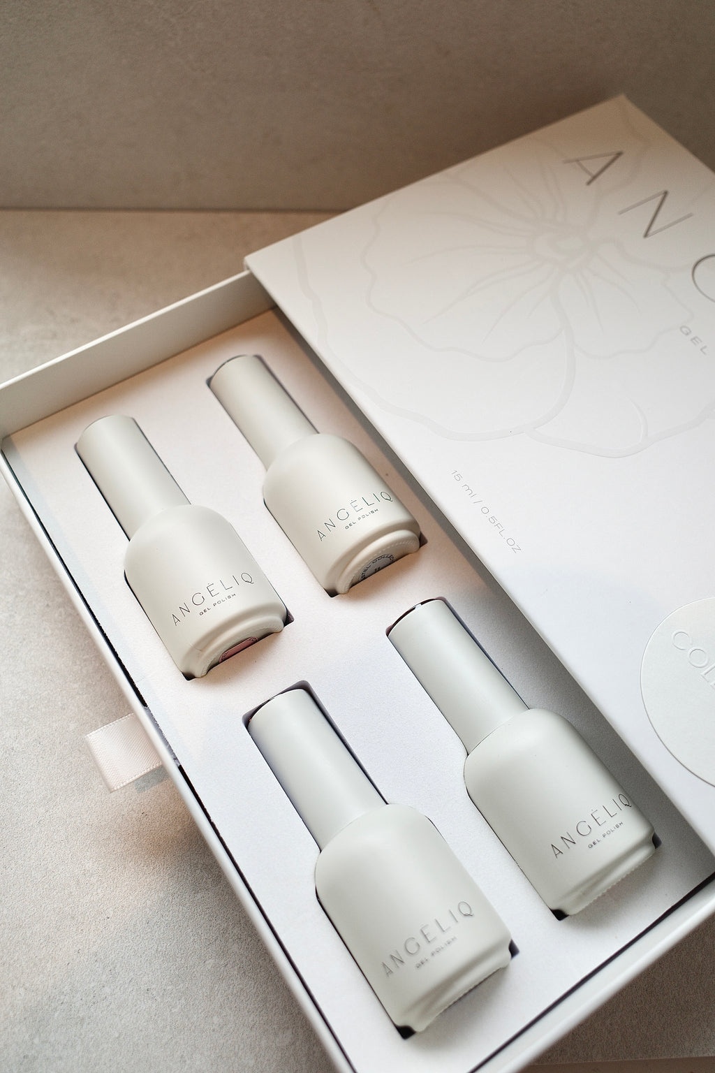 Set of four white nail polish bottles in a box with 'ANGELIQ' branding.
